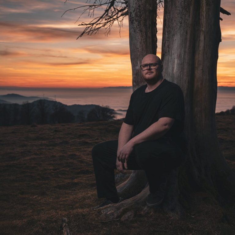 Maenner Portrait in der Natur, im Schwarzwald auf dem Kandel bei Sonnenuntergang mit Blick auf die Landschaft.